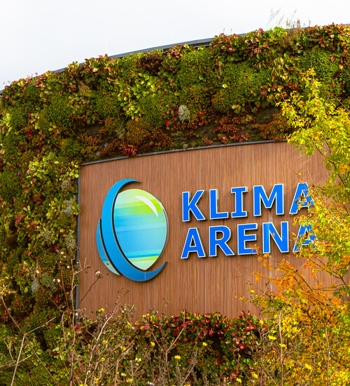 Eine Ansicht der begr&uuml;nten Logowand des Klima Arena Geb&auml;udes von Au&szlig;en